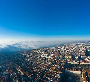 Separated Prints: Aerial; panoramic drone view of foggy Lisbon morning; impending clouds over the ancient ginger roofs; blue skyline