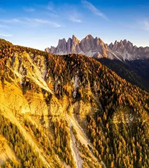 Aerial panoramic of sunset over colorful woods in autumn surrounding the Odle