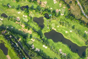 Aerial panoramic view drone shot of beautiful golf course with people playing golf in field
