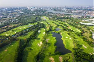 Aerial panoramic view drone shot of beautiful golf course with people playing golf in field and houses in city