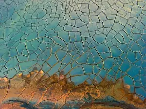 An aerial photograph captures the intriguing textures and contrasting colors of crackled dry mud