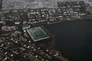 Aerial shot of the Faroese village Sandavagur as seen from a helicopter flight over snow-covered landscape in early