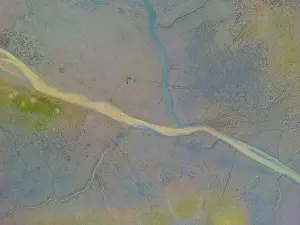 An aerial shot of the landscape with small lake surrounded by trees and field