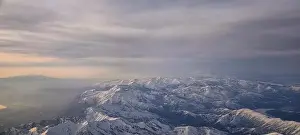 Sunset Mountain Prints: Aerial view from airplane of the Wasatch Front Rocky Mountain Range with snow capped peaks in winter including urban