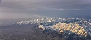 Sunset Mountain Prints: Aerial view from airplane of the Wasatch Front Rocky Mountain Range with snow capped peaks in winter including urban
