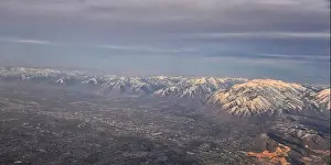 Sunset Mountain Prints: Aerial view from airplane of the Wasatch Front Rocky Mountain Range with snow capped peaks in winter including urban