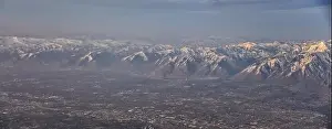 Sunset Mountain Prints: Aerial view from airplane of the Wasatch Front Rocky Mountain Range with snow capped peaks in winter including urban