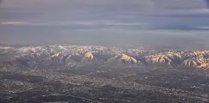 Sunset Mountain Prints: Aerial view from airplane of the Wasatch Front Rocky Mountain Range with snow capped peaks in winter including urban