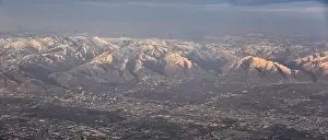 Sunset Mountain Prints: Aerial view from airplane of the Wasatch Front Rocky Mountain Range with snow capped peaks in winter including urban