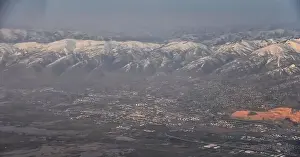 Sunset Mountain Prints: Aerial view from airplane of the Wasatch Front Rocky Mountain Range with snow capped peaks in winter including urban