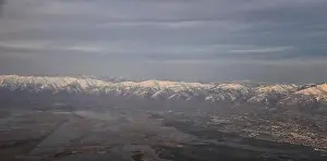 Sunset Mountain Prints: Aerial view from airplane of the Wasatch Front Rocky Mountain Range with snow capped peaks in winter including urban