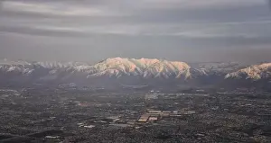Sunset Mountain Prints: Aerial view from airplane of the Wasatch Front Rocky Mountain Range with snow capped peaks in winter including urban