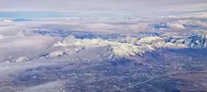 Sunset Mountain Prints: Aerial view from airplane of the Wasatch Front Rocky Mountain Range with snow capped peaks in winter including urban
