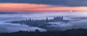 Alcazar Prints: Aerial view of ancient town and medieval Alcazar de Toledo palace in mist in colorful daybreak