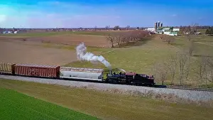 Puffing Prints: Aerial View of an Antique Steam Engine Doing Switching Dues at a Freight Yard in the Middle of Farmlands on a Sunny Day