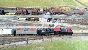 Puffing Prints: Aerial View of an Antique Steam Engine Doing Switching Dues at a Freight Yard in the Middle of Farmlands on a Sunny Day