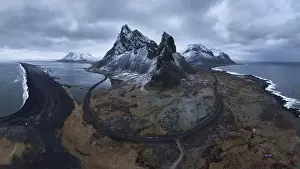 Eystrahorn Prints: Aerial view of asphalt road going between snowy mountain and blue ocean under cloudy sky in Eystrahorn