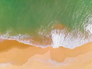 Aerial view of a beach and waves along the sea