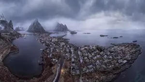 Inhabited Prints: Aerial view of calm water of sea washing island with a village and rocky formations under cloudy sky