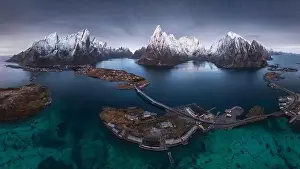 Inhabited Prints: Aerial view of calm water of sea washing island with a village and rocky formations under cloudy sky