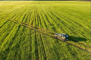 Aerial view of car SUV parked near countryside road in field rural landscape. Bird's-eye drone view of car SUV parked near countryside road in summer