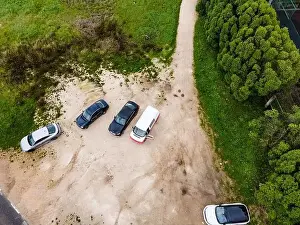 High View Prints: Aerial view of a few cars parked in a small parking lot along the road on Monsanto Hill next a football field