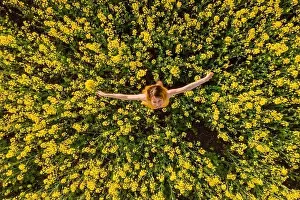 Trending Prints: Aerial view of cheerful woman at blooming rapeseed field. Yellow flowers and happy woman