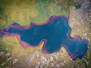 Uneven Prints: Top aerial view of colorful lake water surrounded by green grass and stones in daylight in nature of Pyrenees