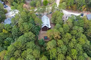 Aerial view of cottages and cars parked nearby in the woods among green trees