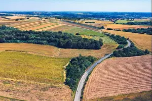 Aerial view of a country road amid fields against blue clear sky