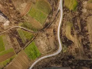 Parcels Prints: Aerial view top down from above on the country road in mountain range in between fields grass