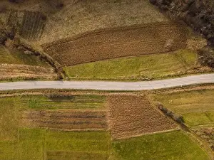 Parcels Prints: Aerial view top down from above on the country road in mountain range in between fields grass