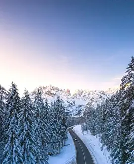 Misurina Prints: Aerial view by drone of car traveling on the scenic road Dobbiaco-Misurina along snowy woods at dawn
