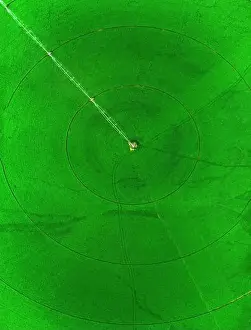 Mowing Prints: Aerial view from a drone flying above a green farm field growing crops growth with irrigation pivot sprinklers