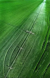 Furrow Prints: Aerial view from a drone flying above a green farm field growing crops growth with irrigation pivot sprinklers