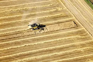 Agribusiness Prints: An aerial view of farm machinery in the field harvesting wheat