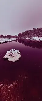 Forest River Prints: An aerial view of a frozen river flowing through snow-covered forests on a cloudy sunset sky background