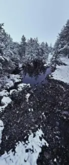 Forest River Prints: An aerial view of a frozen river flowing through snow-covered forests on a cloudy sunset sky background