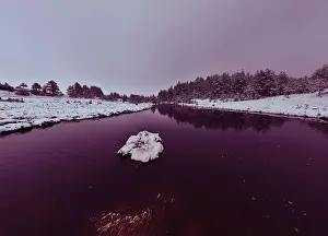 Forest River Prints: An aerial view of a frozen river flowing through snow-covered forests on a cloudy sunset sky background