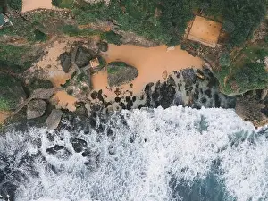 Top down aerial view of giant ocean waves crashing and foaming in coral beach