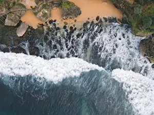 Yogyakarta Prints: Top down aerial view of giant ocean waves crashing and foaming in coral beach