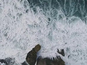 Yogyakarta Prints: Top down aerial view of giant ocean waves crashing and foaming in coral beach