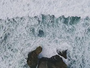 Yogyakarta Prints: Top down aerial view of giant ocean waves crashing and foaming in coral beach