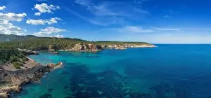 aerial view the green and rugged hilly coast of northern Ibiza with the turquoise waters of Cala Xarraca bay