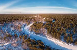 Aerial view of a heart shaped winter forest with frozen river