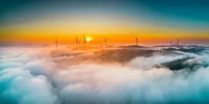 Morning Glow Prints: Aerial view top hill at dawn with fog covering small village in valley