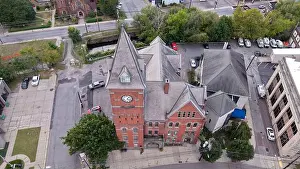Brickwork Prints: Aerial view of a historic brick building with a prominent clock tower standing tall amidst the urban landscape