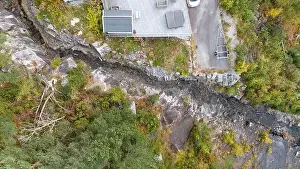Directly Above Prints: Aerial view of a house near a rocky cliff with a small mountain river