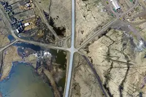 Aerial view of the intersection of asphalt and ground roads in the field far from the big cities on a clear spring day