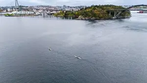 Outdoor Activity Prints: Aerial view of two kayakers paddling on a calm fjord near a bridge and small island